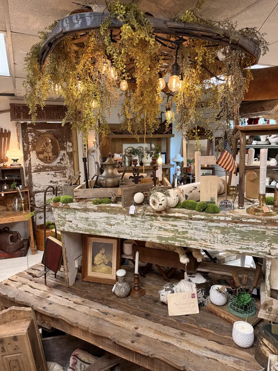Layered vendor booth with vintage furniture, garden greenery, and collected decor