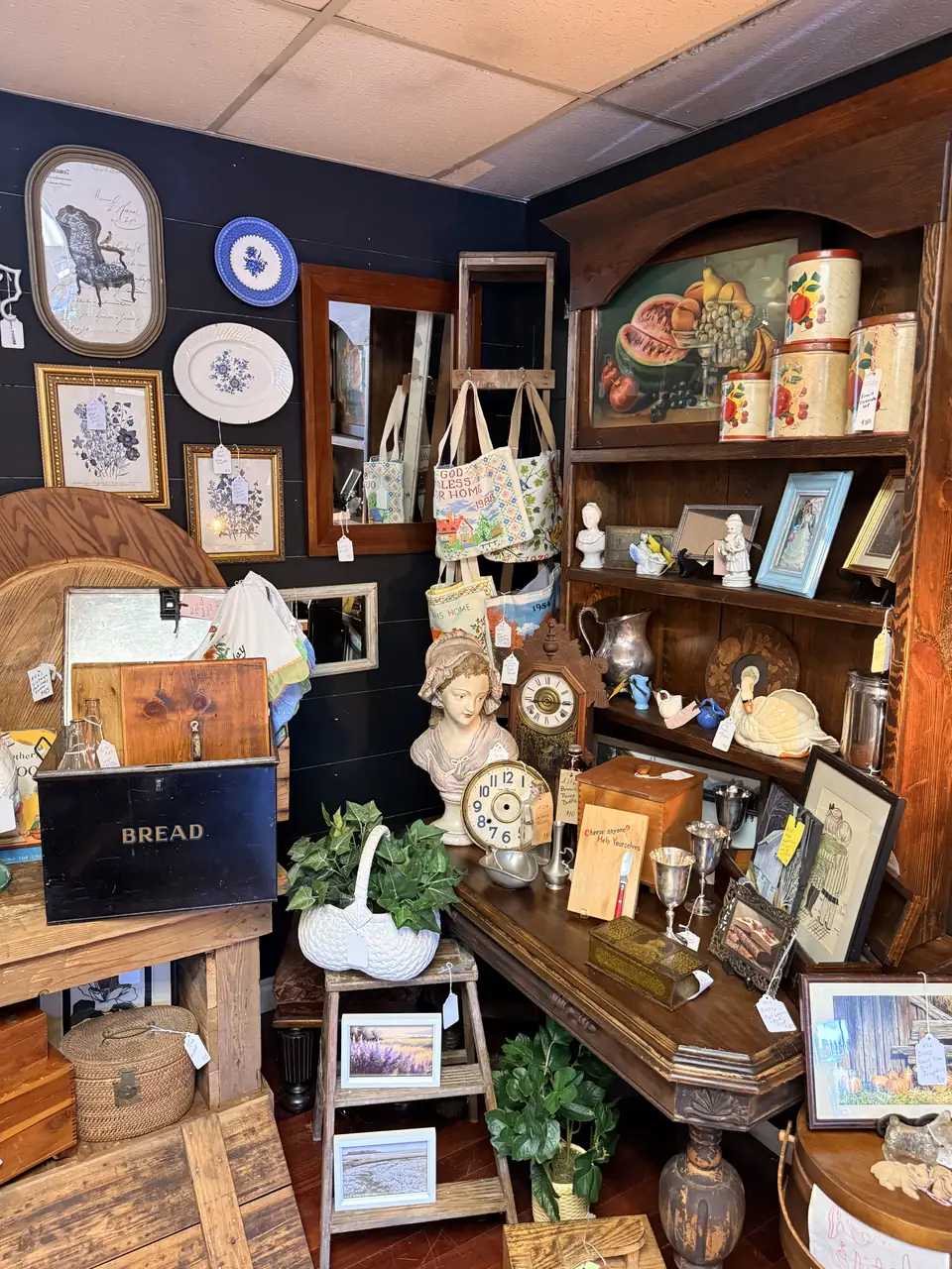 Antiques booth layered with wood furniture, framed art, and collected decor