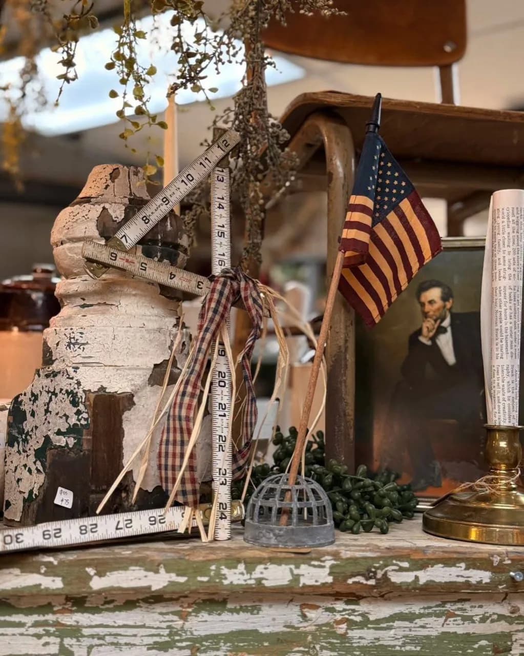 Americana vignette with an antique measuring tape, flag, portrait, and weathered wood