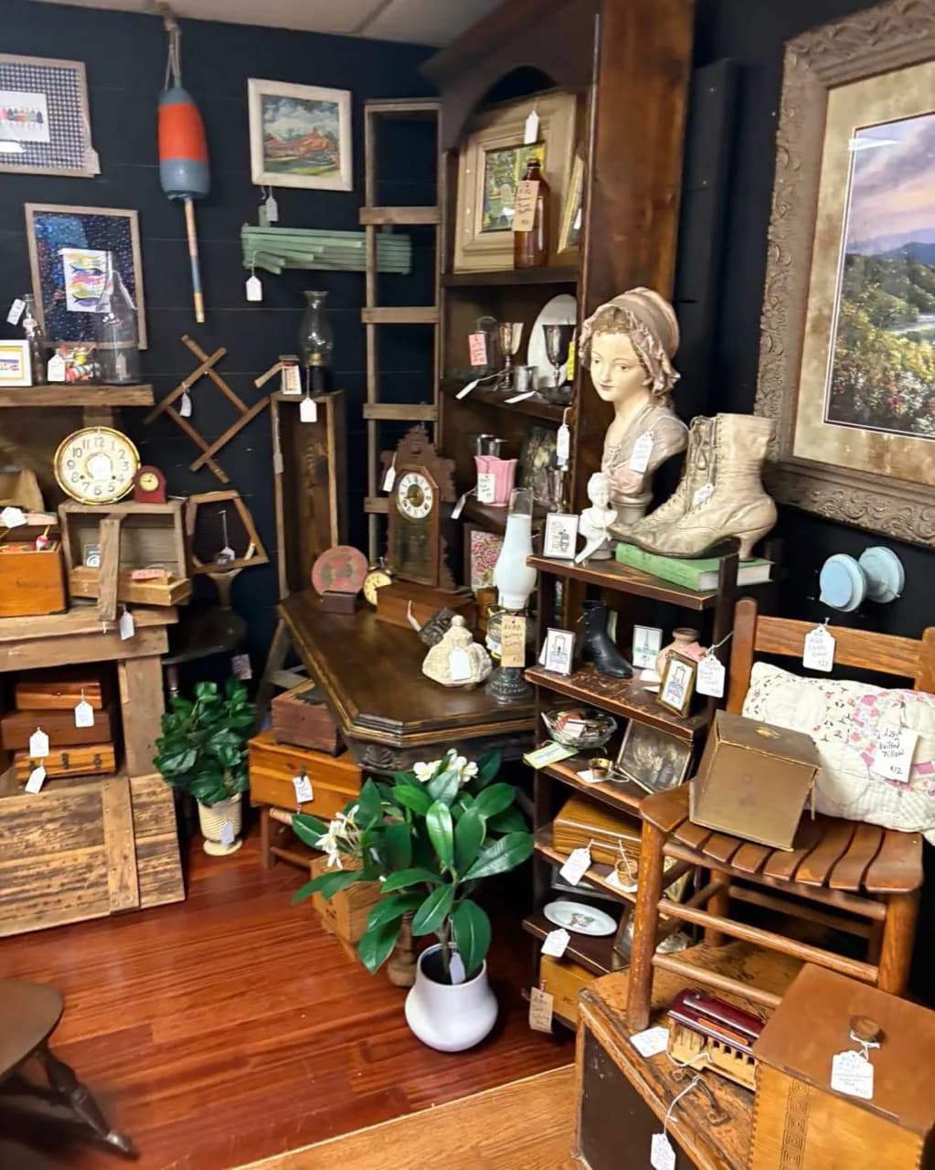 Antique booth filled with clocks, framed art, wooden furniture, and collectibles