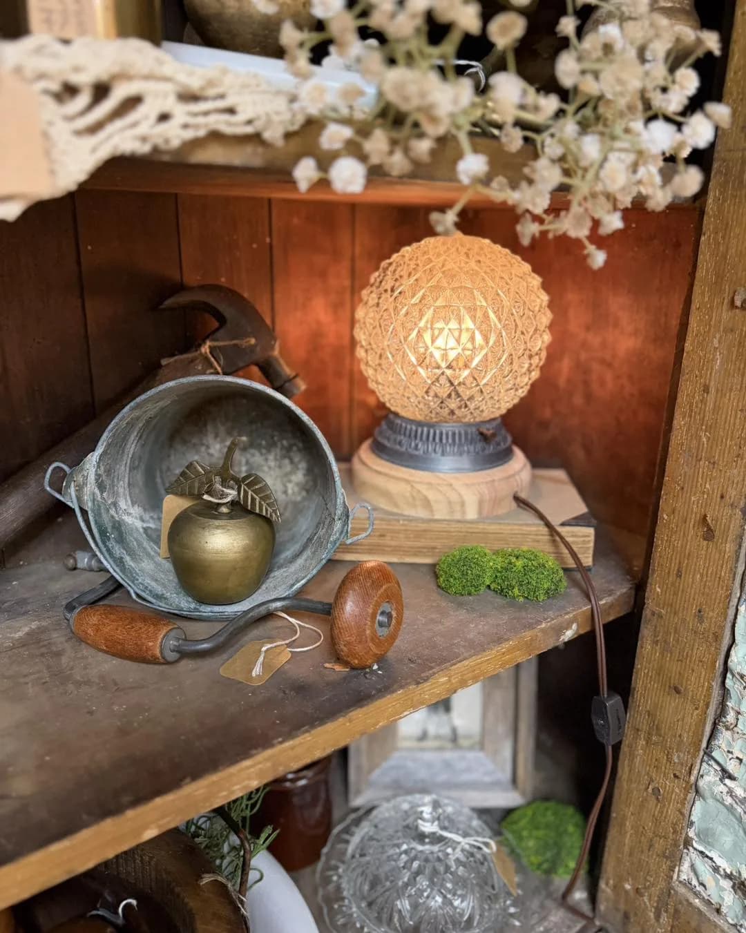 Brass apple, crystal lamp, and collectibles arranged on a vendor shelf