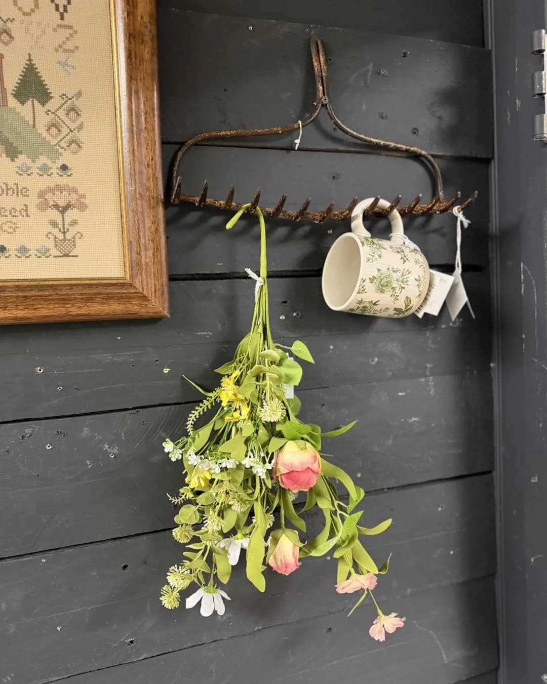 Rustic rake hook with florals and a mug in a farmhouse vignette