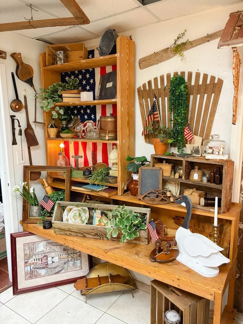 Rustic vendor display with plants, vintage tools, flags, art, and wooden shelves