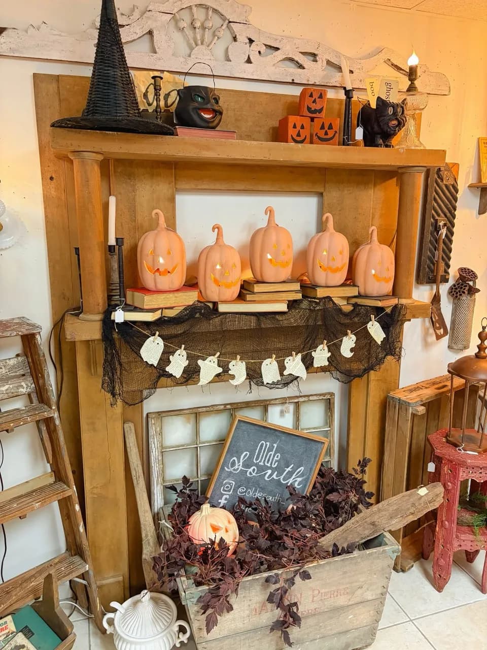 Pumpkins, ghost garland, and vintage Halloween decorations arranged on the Olde South mantel