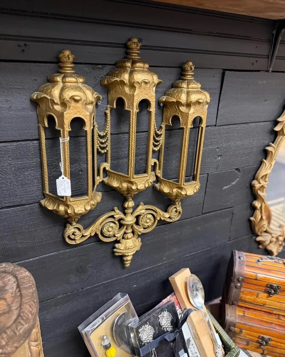 Ornate gold-tone three-light wall sconce displayed at Vintage 72