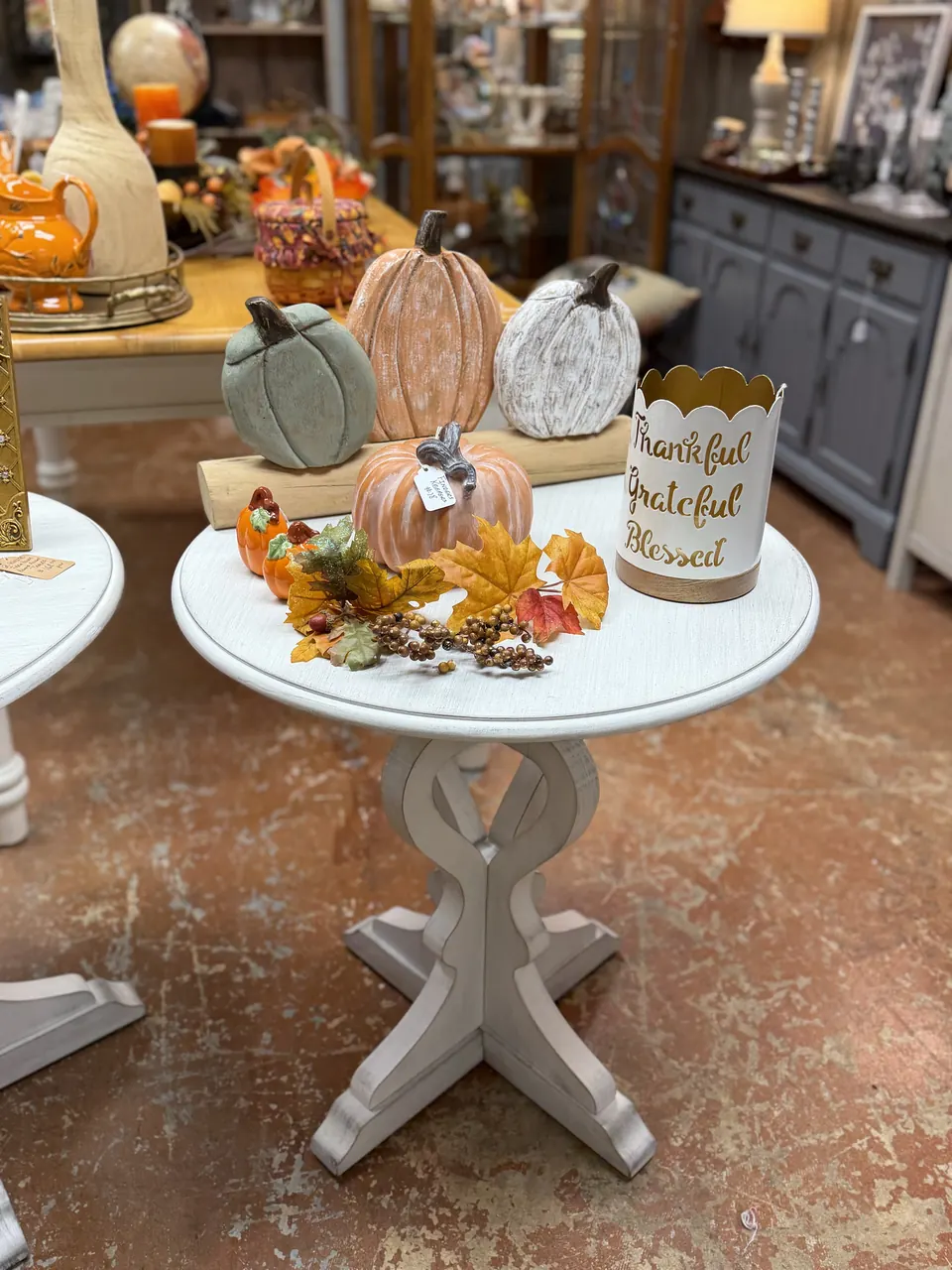 Ceramic pumpkins and a Thankful, Grateful, Blessed bucket on a white pedestal table at Vintage 72